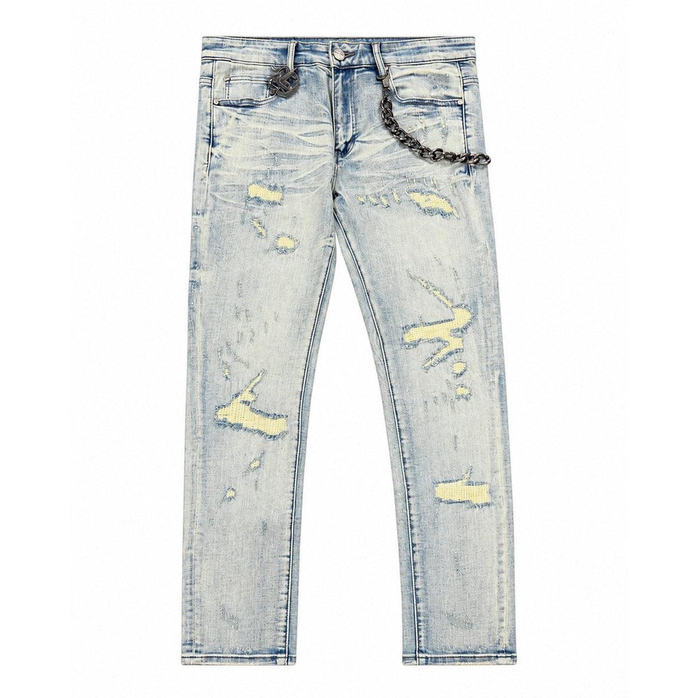 Light wash skinny jeans with heavy distressing, yellow underlay patches, and a detachable metal chain accessory.