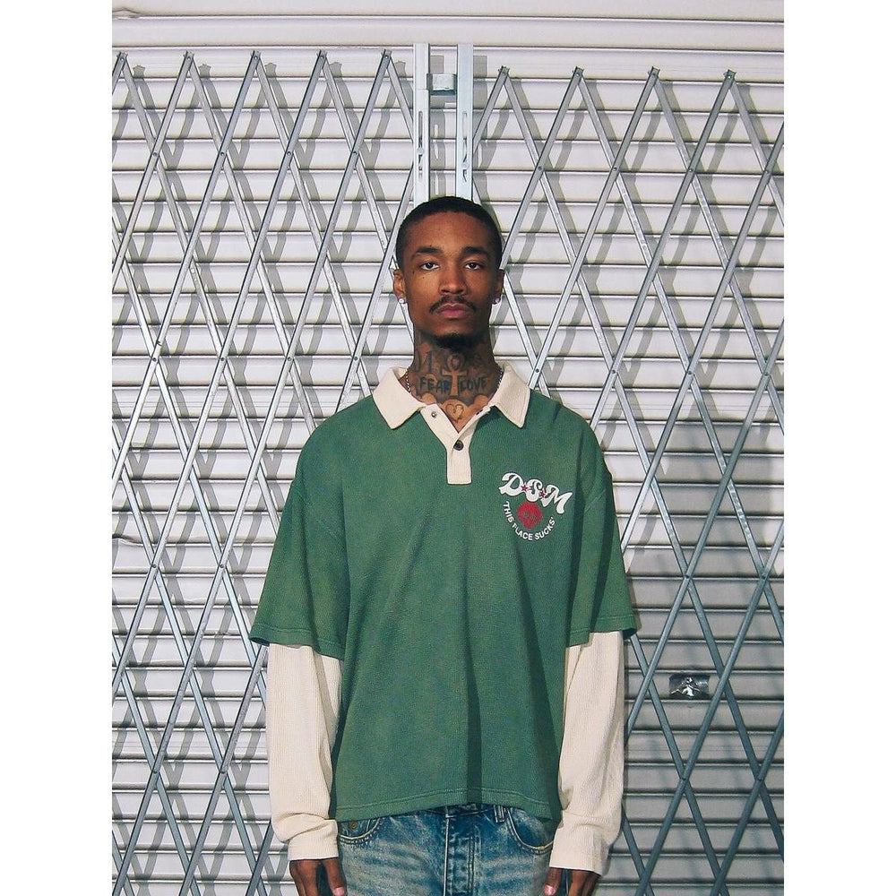 Green waffle-knit long sleeve polo with a cream collar, layered sleeves, and a DSM chest graphic.