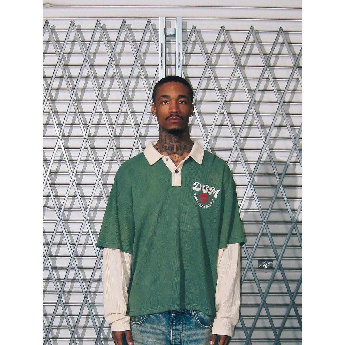 Green waffle-knit long sleeve polo with a cream collar, layered sleeves, and a DSM chest graphic.
