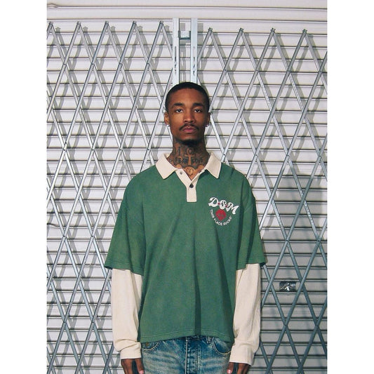 Green waffle-knit long sleeve polo with a cream collar, layered sleeves, and a DSM chest graphic.