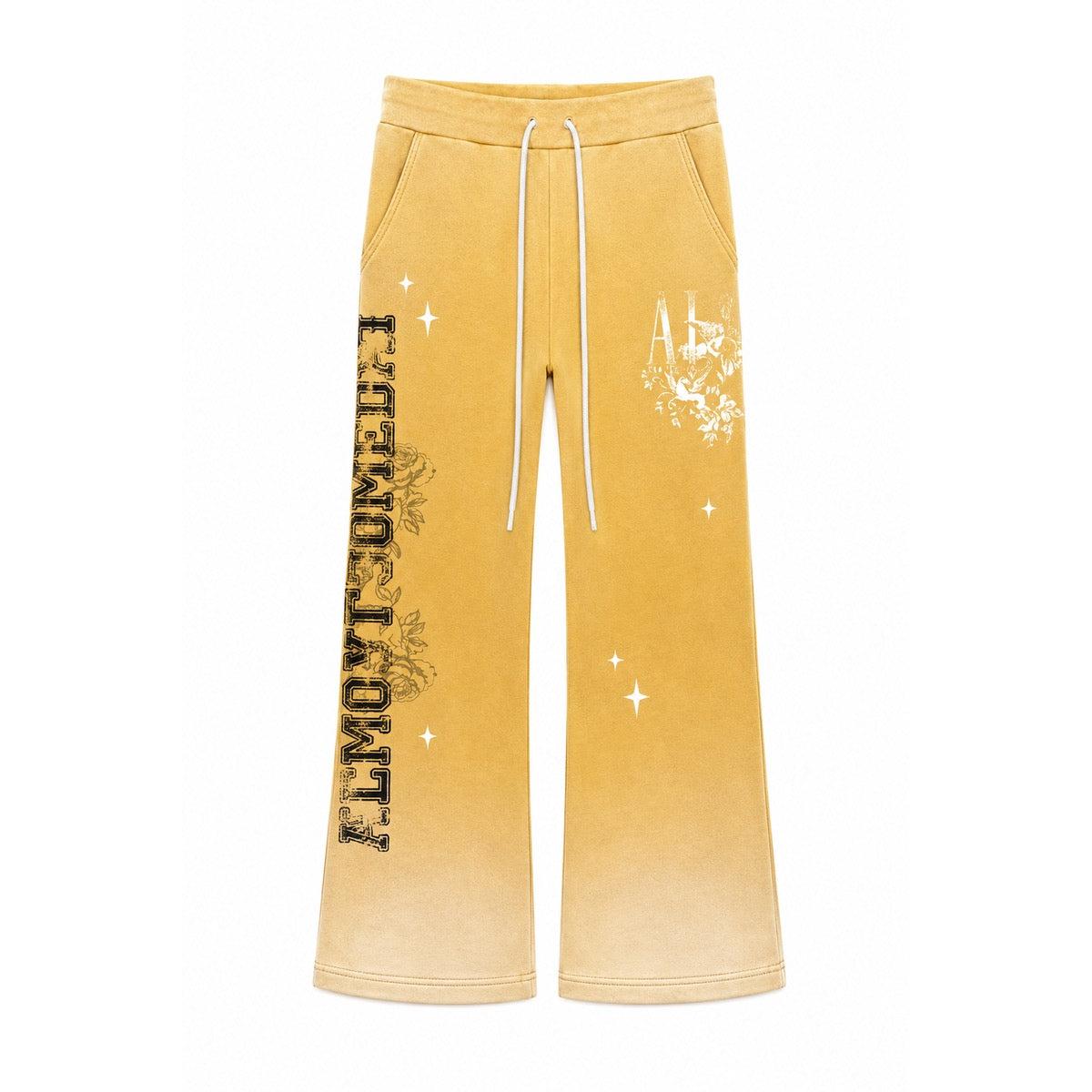 Yellow flared sweatpants with white drawstring, floral graphics, and Almost Someday text in a relaxed streetwear fit.