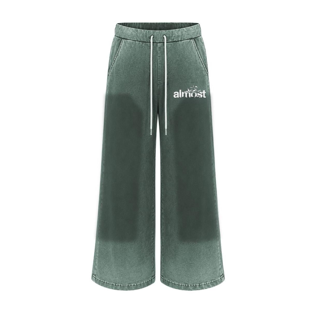 Green flared sweatpants with a vintage wash, white drawstring waist, and Almost Someday graphic logo on the hip.
