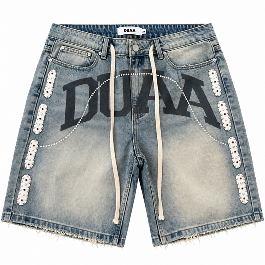Duaa blue wash denim jorts featuring a large black logo, white studded side panels, and a raw frayed hem.