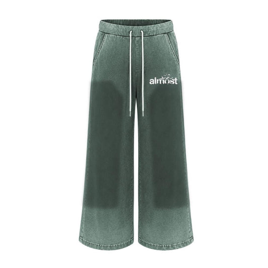 Green flared sweatpants with a vintage wash, white drawstring waist, and Almost Someday graphic logo on the hip.